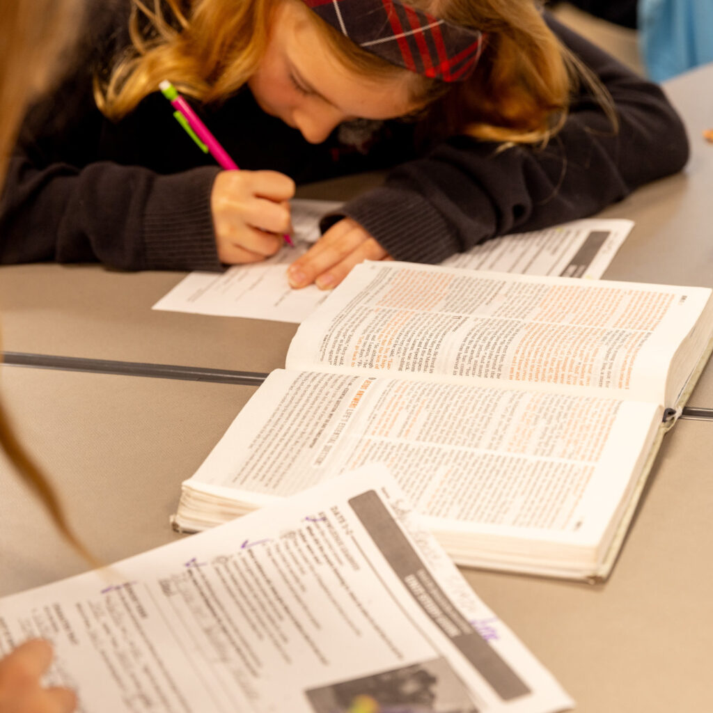A student writes notes while working on an assignment out of her textbook during class.