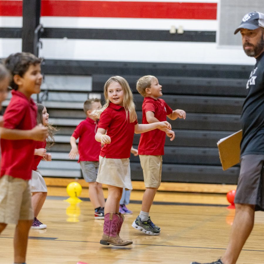 Elementary students line dancing in gym with coach