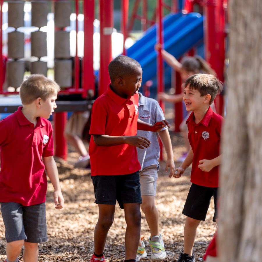 Four young students laugh and play during their recess on the school's playground.