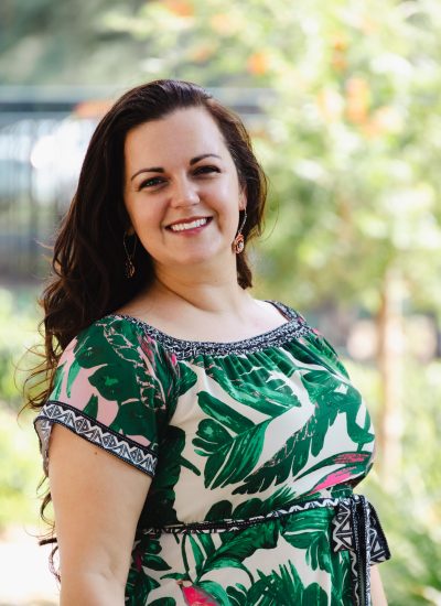 Rachel Leightman smiles in a green tropical print dress outdoors.