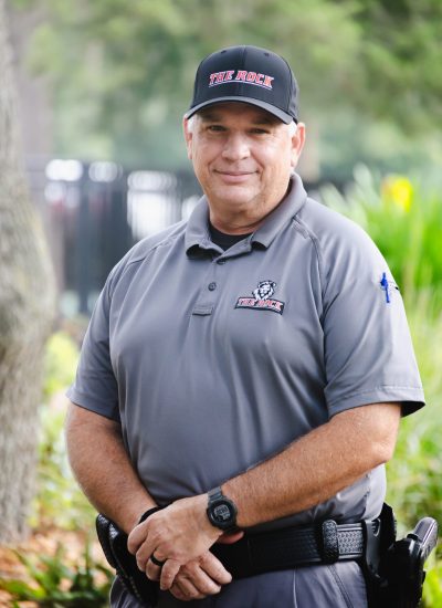 Portrait of Brett Sandlin in uniform with "The Rock" hat and shirt logo.