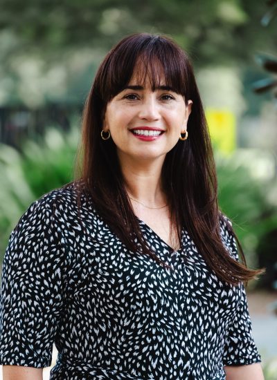 Sandra Gonzalez, smiling woman with dark hair, wearing a patterned black and white dress.